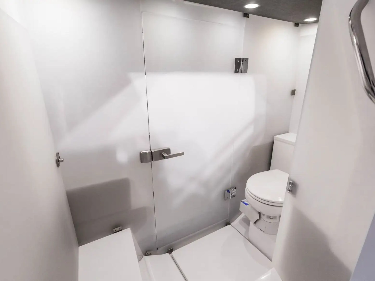 Compact white bathroom with toilet and glass door shower.