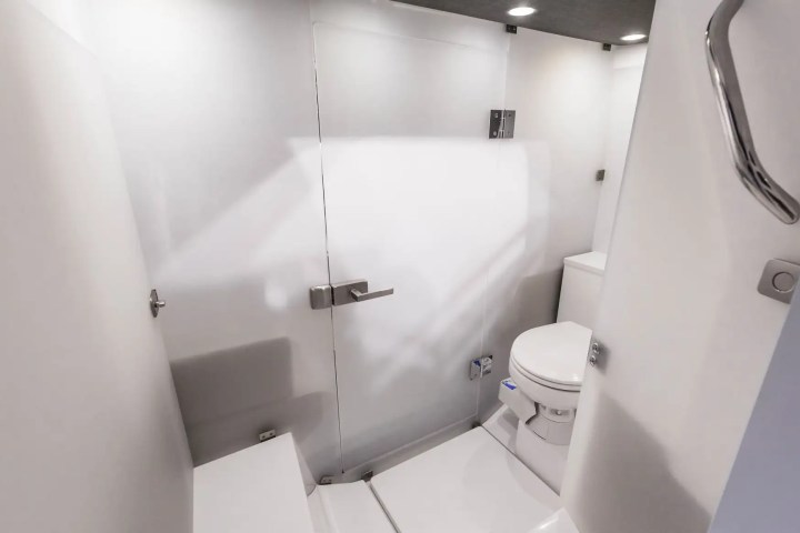 Compact white bathroom with toilet and glass door shower.