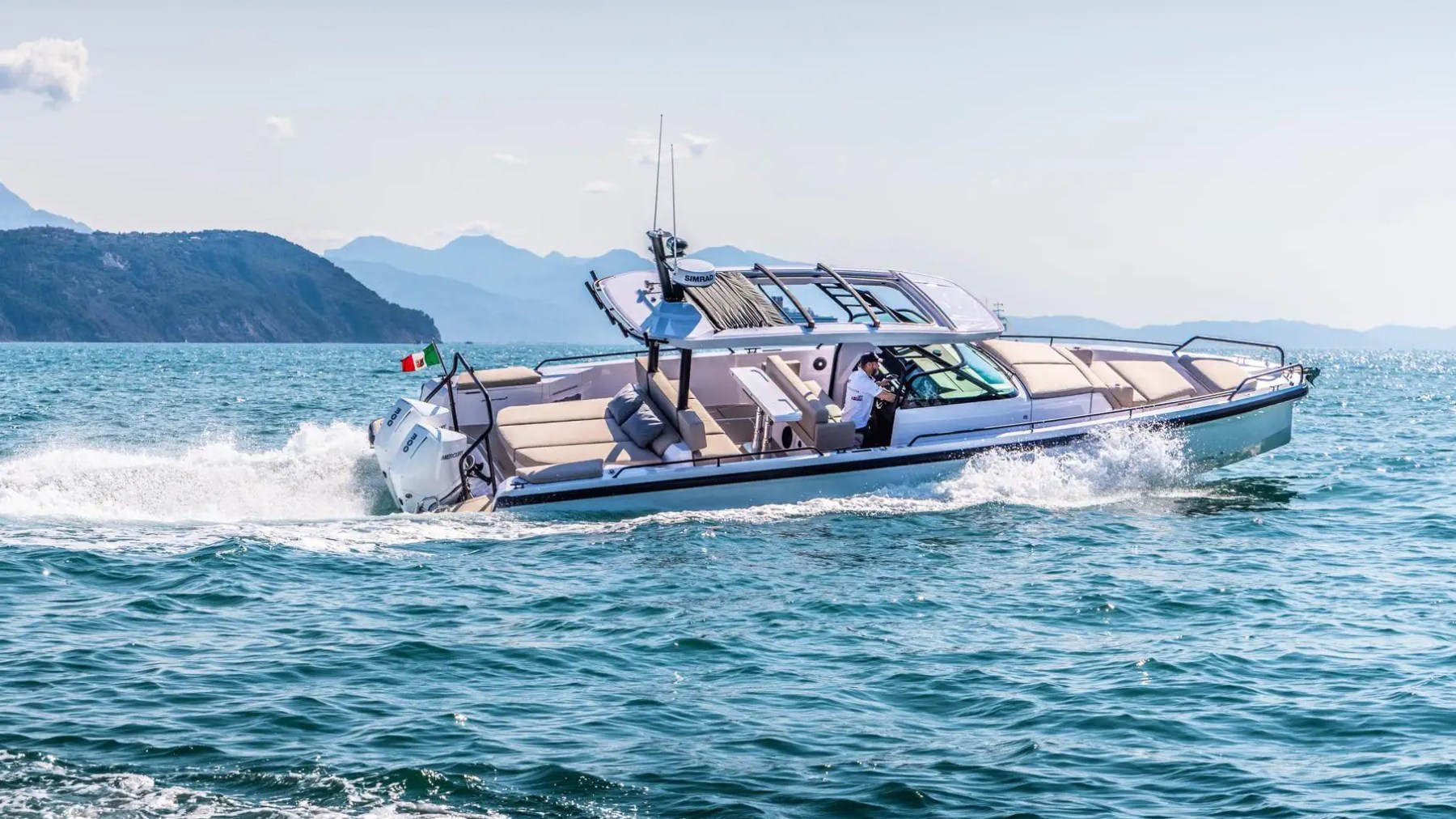 Motorboat cruising on open water with mountains in the background.