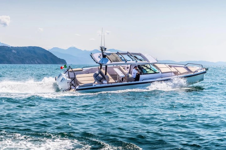 Motorboat cruising on open water with mountains in the background.