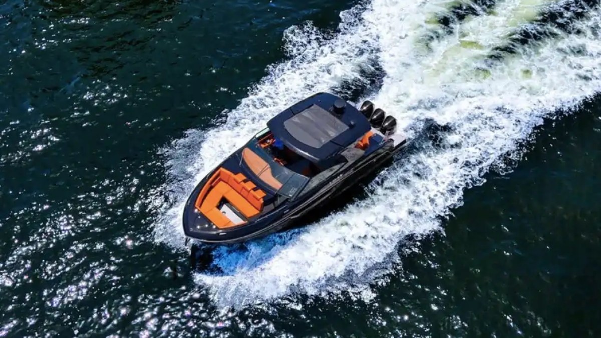 A luxury speedboat with orange seats speeding on a dark blue sea, leaving a frothy wake behind.