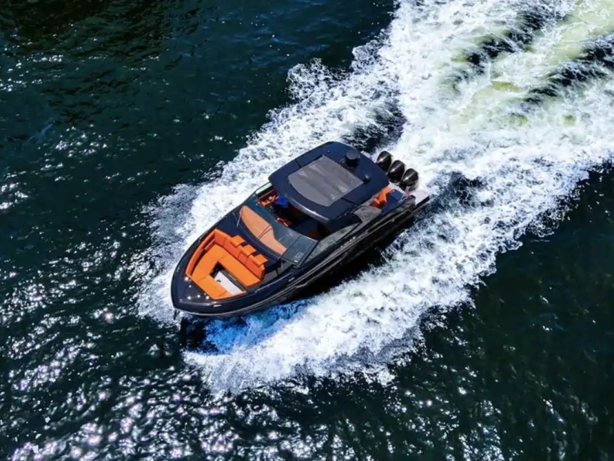 A luxury speedboat with orange seats speeding on a dark blue sea, leaving a frothy wake behind.