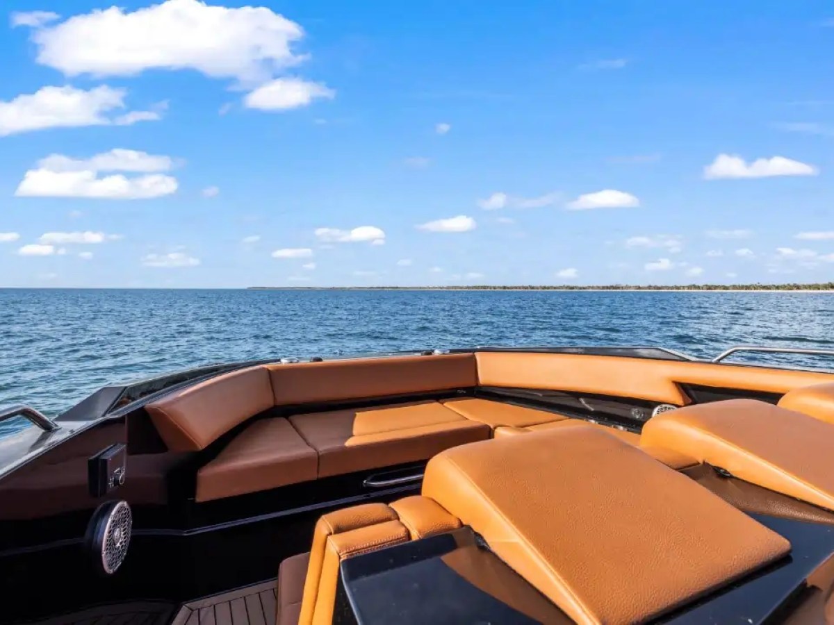 This 38 foot Cruisers Boat Rental features a spacious open bow lounge with wraparound seating and sun pads overlooking Gulf Coast waters near Naples on a clear Southwest Florida day.