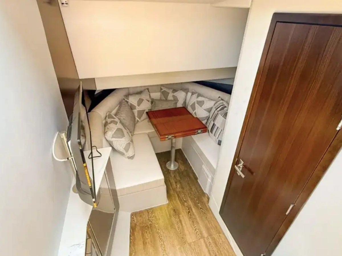 This 38 foot Cruisers Boat Rental features a private cabin retreat with wraparound seating, wood dining table, accent cushions, and warm interior finishes while cruising Naples and Southwest Florida waters.