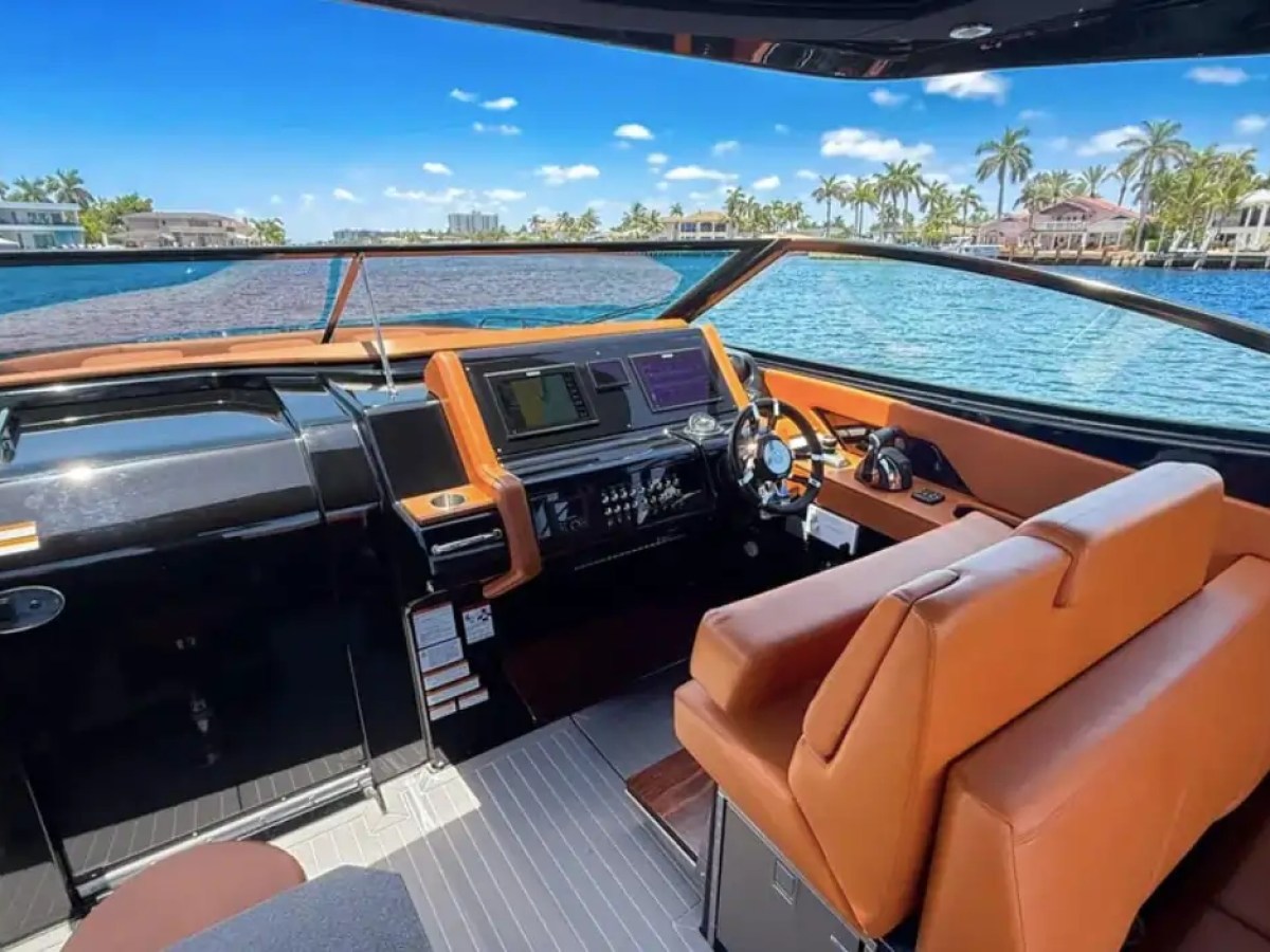 This 38 foot Cruisers Boat Rental features a modern helm station with tan seating, navigation displays, and panoramic water views while cruising Naples waterways.