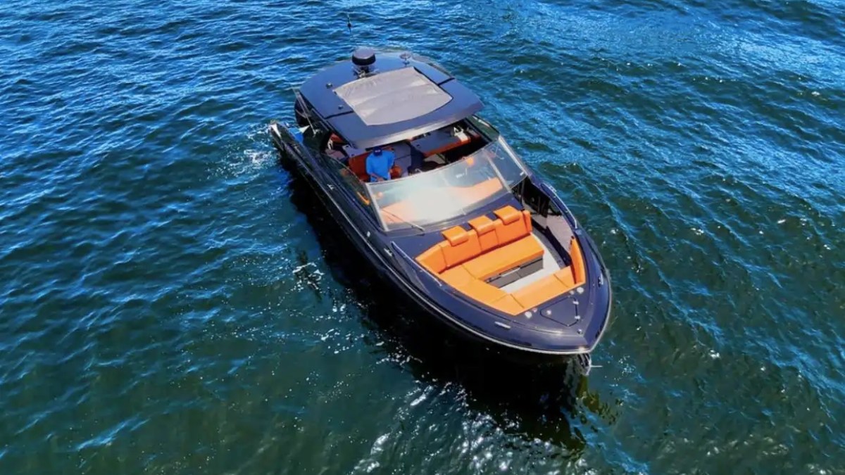 Aerial view of a sleek black motorboat with orange seating on blue water.
