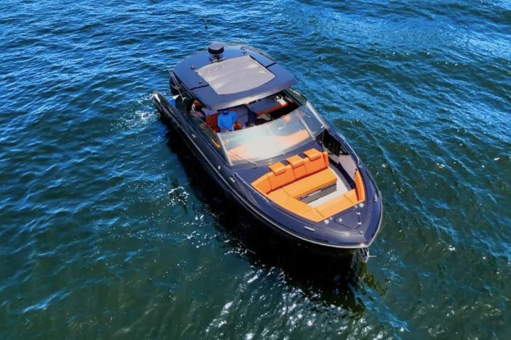 Aerial view of a sleek black motorboat with orange seating on blue water.