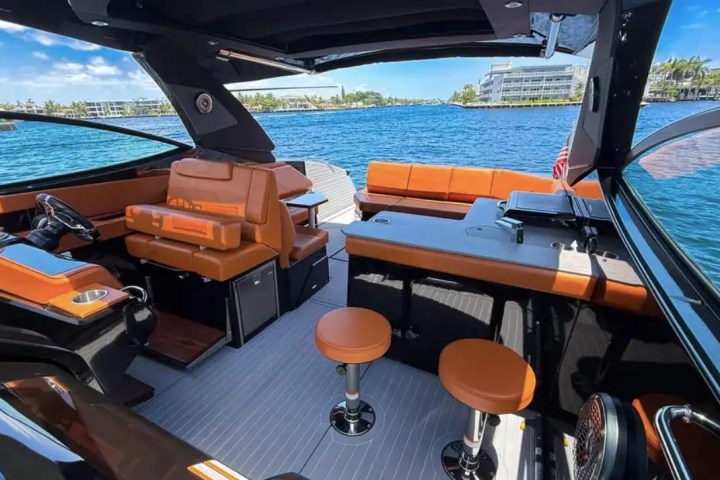 Interior of a luxury boat with orange seating and a view of the ocean.