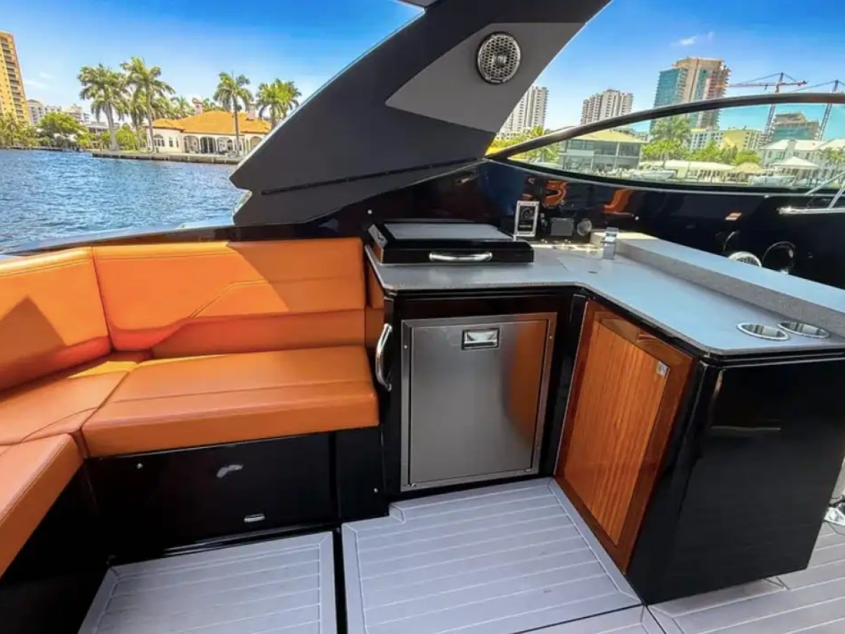 This 38 foot Cruisers Boat Rental features an aft entertainment area with wraparound seating, countertop workspace, storage cabinetry, and Naples waterfront views along the Intracoastal Waterway.