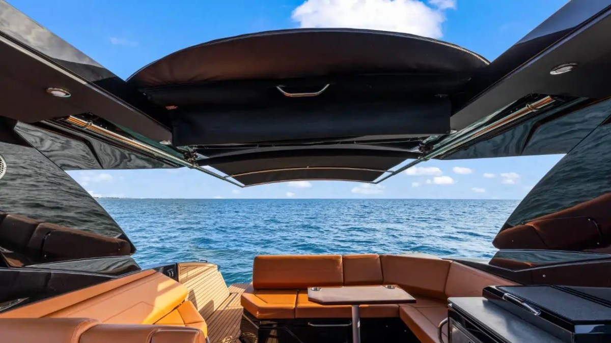 View from a yacht's deck with seating under a canopy, looking out to the ocean.