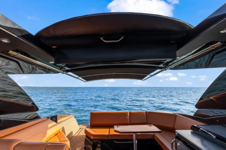 View from a yacht's deck with seating under a canopy, looking out to the ocean.