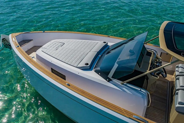 Luxury boat with cushioned deck and steering area, floating on clear turquoise water.