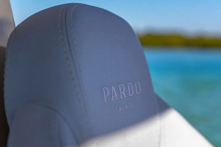 Close-up of a gray leather seat with 'PARDO' embossed, against a blurry blue water background.