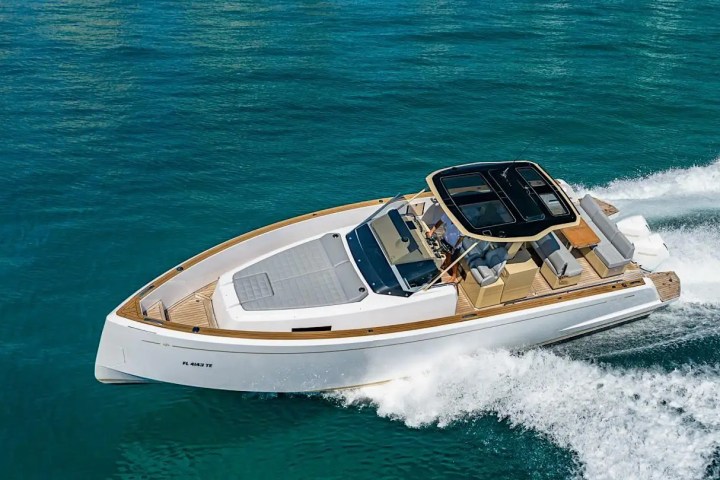 A sleek white motorboat cruising on turquoise water with a spacious deck.