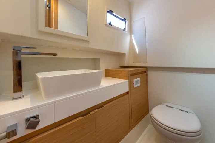 Compact bathroom with a white sink, modern faucet, wooden cabinets, and a toilet.