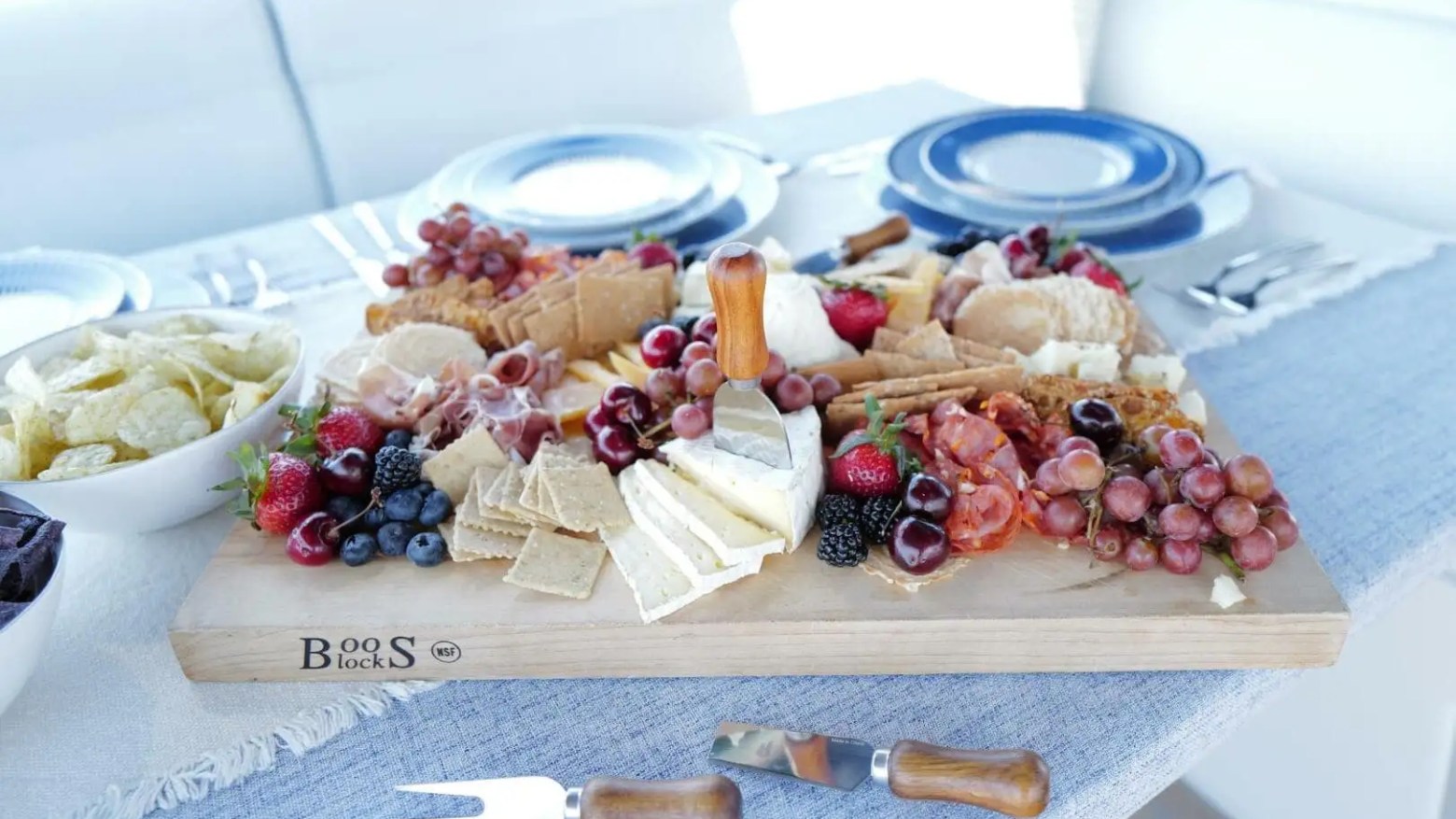Charcuterie board with cheeses, fruits, and meats on a table with plates.