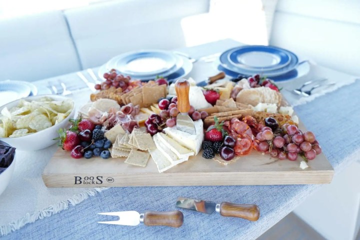 Charcuterie board with cheeses, fruits, and meats on a table with plates.