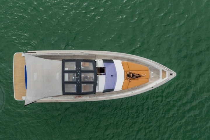 Aerial view of a yacht with a person sunbathing on the deck in the middle of the open water.