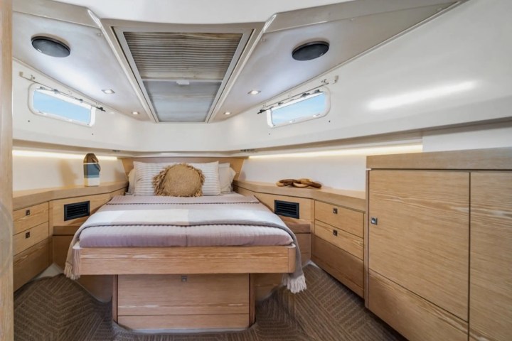 Cozy yacht bedroom with wooden decor, bed, and circular windows.