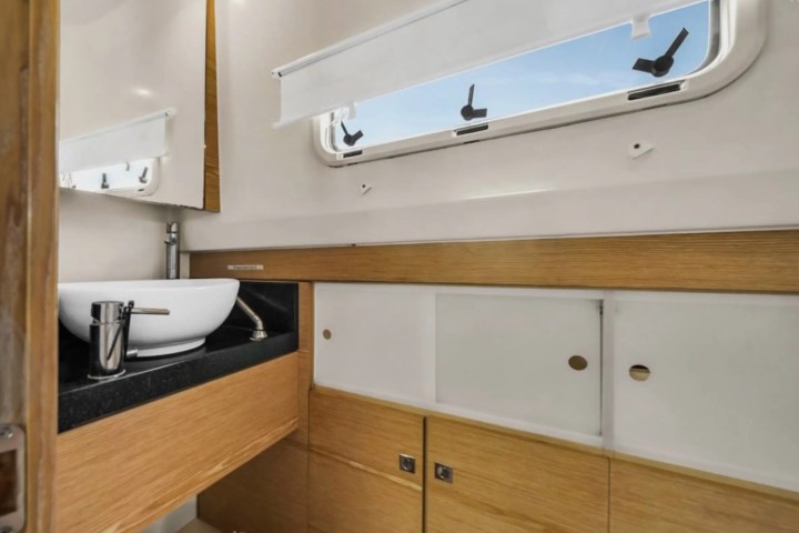 Modern bathroom with a vessel sink, wooden cabinets, and a window with blinds.