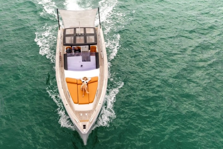 Top view of a yacht on green water with a person sunbathing on the deck.
