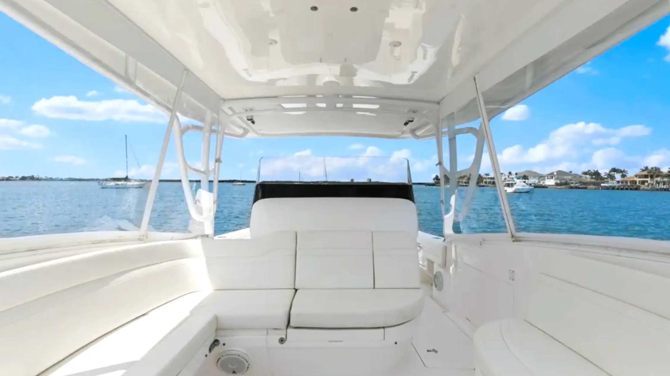 Interior view of a boat with white seats overlooking a calm blue sea.