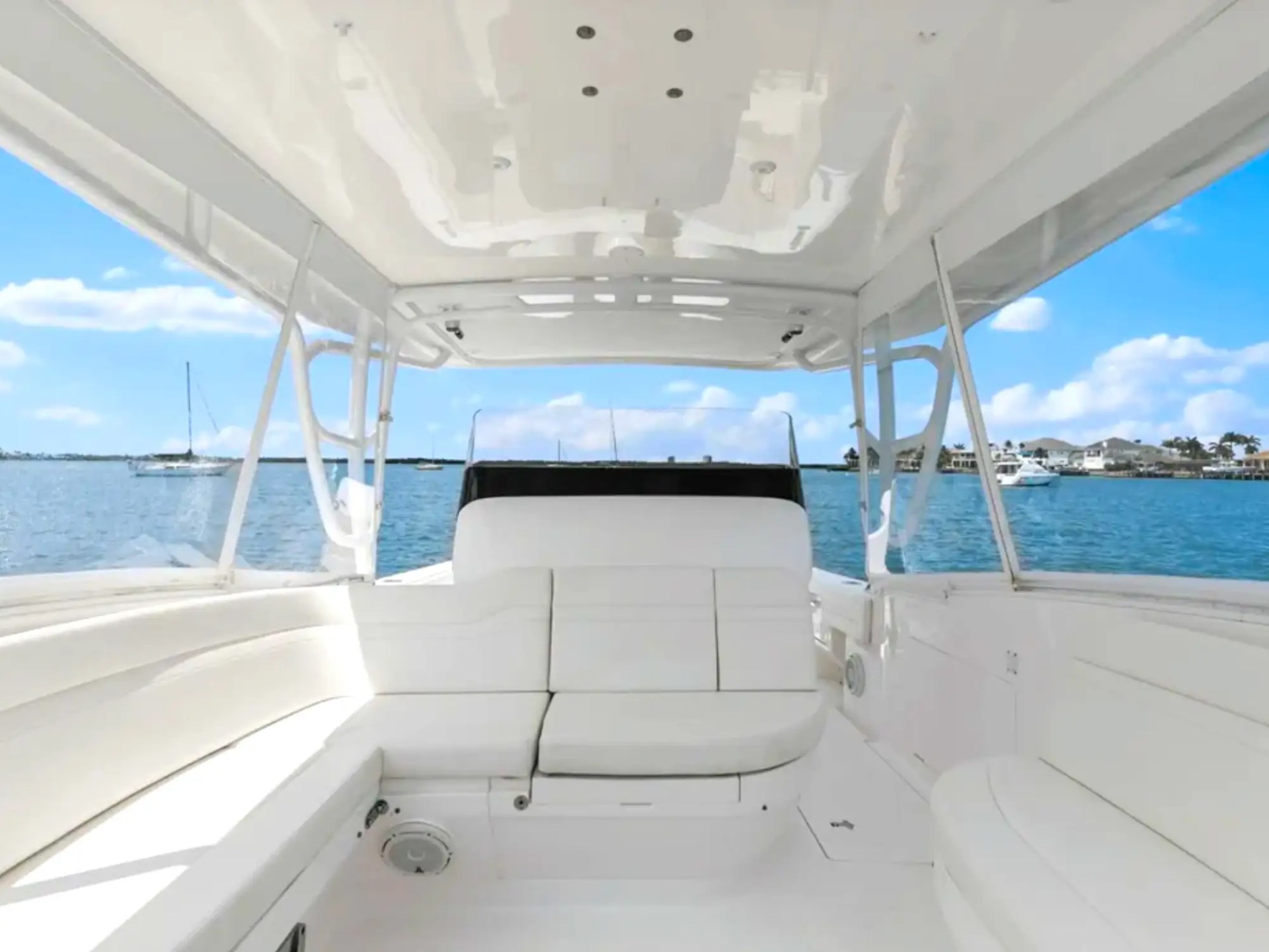 Interior view of a boat with white seats overlooking a calm blue sea.
