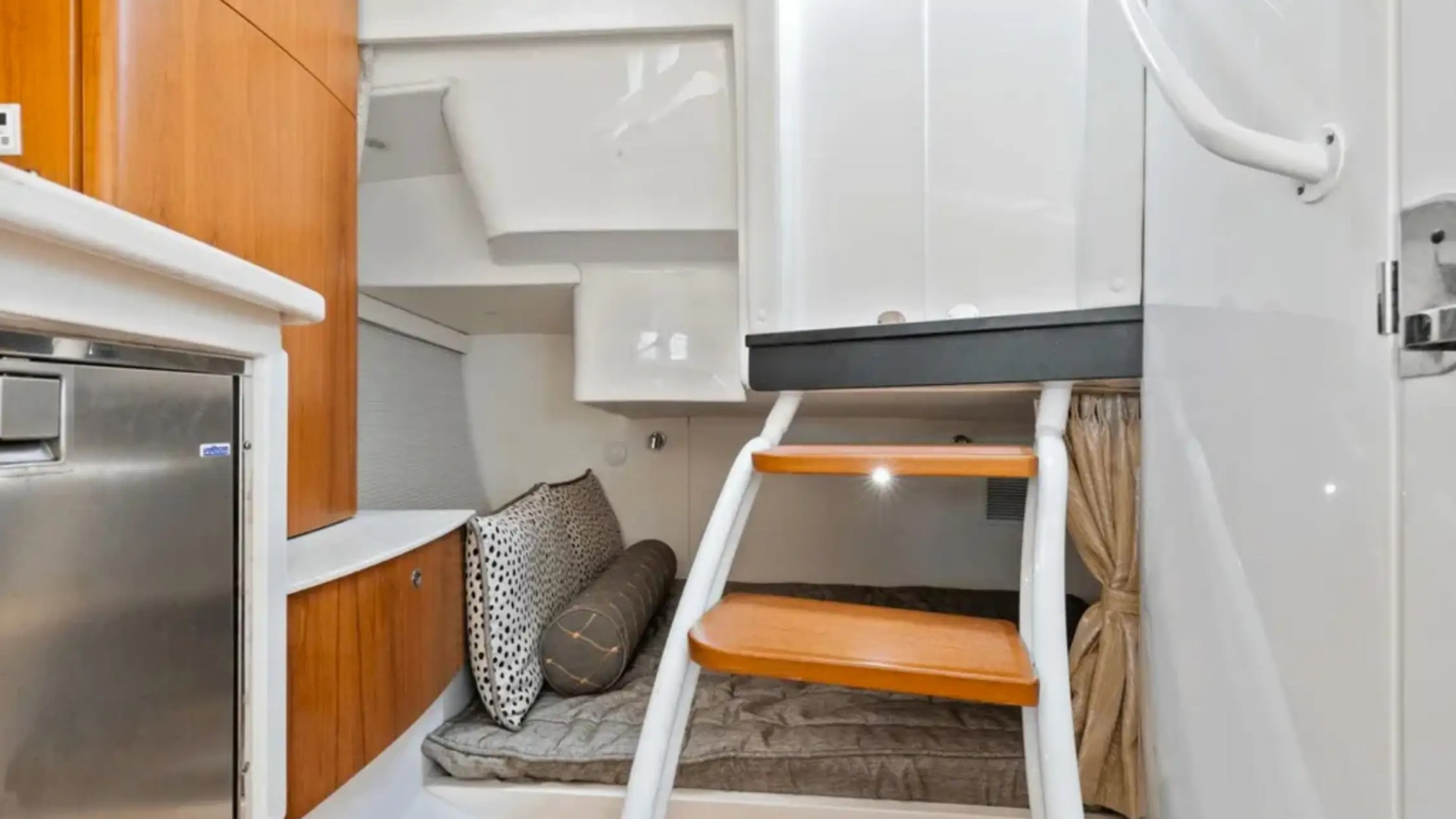 Boat cabin interior with steps and cozy seating area.