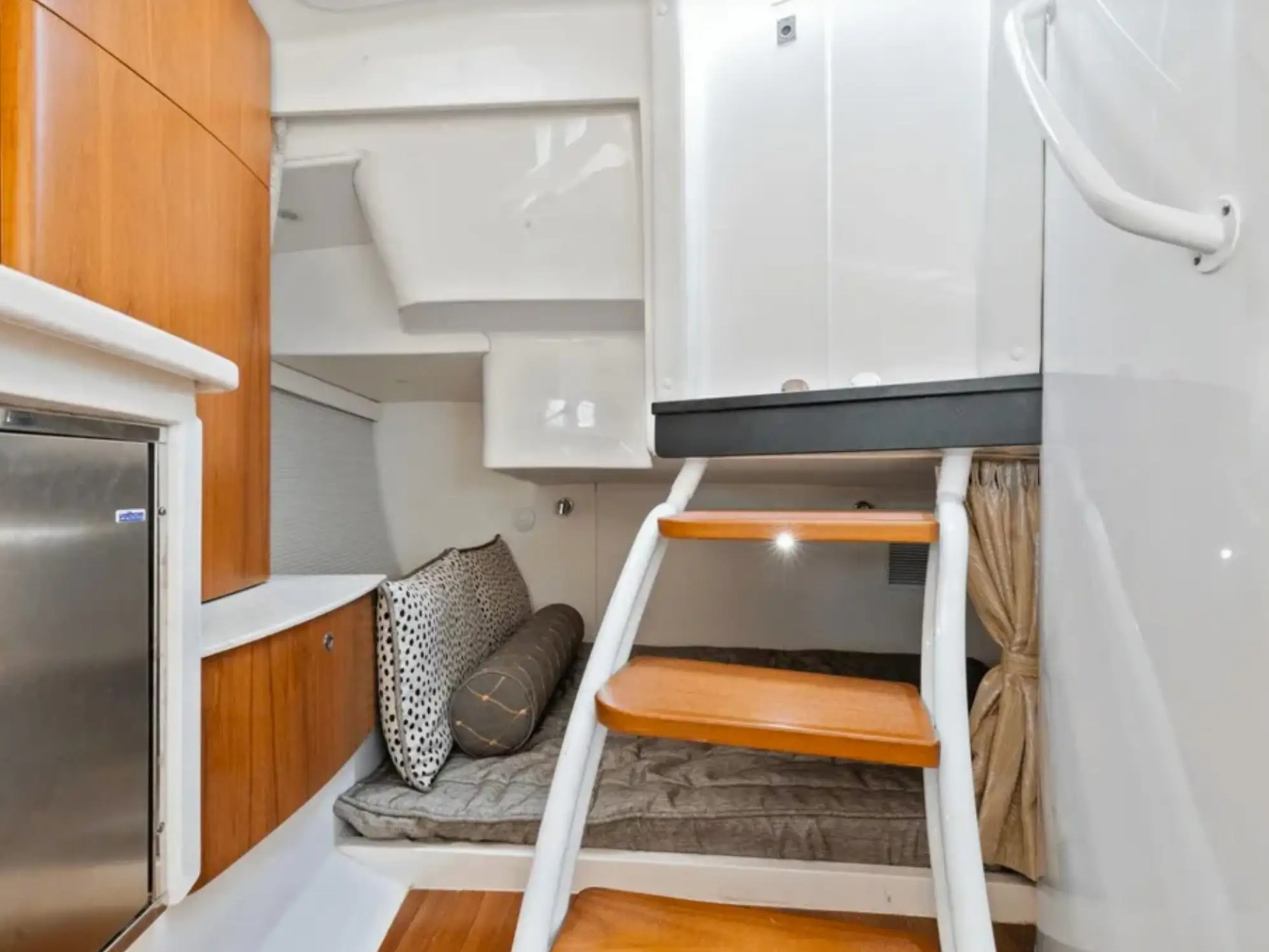 Boat cabin interior with steps and cozy seating area.
