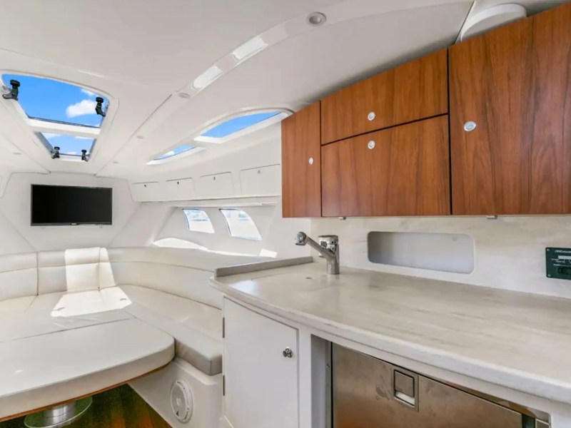 Interior of a yacht with white seating, TV, and wooden cabinets.