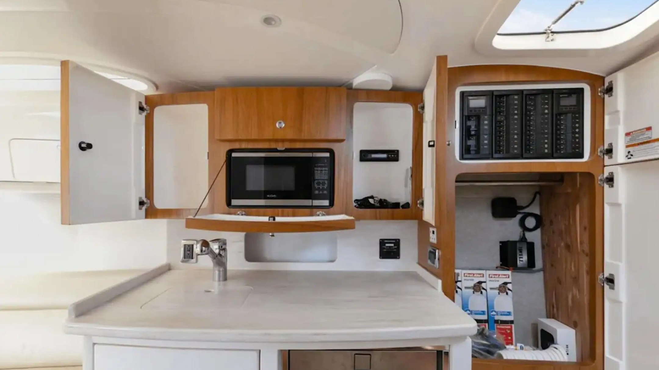 Boat kitchen with microwave, open cabinets, and electrical panels.