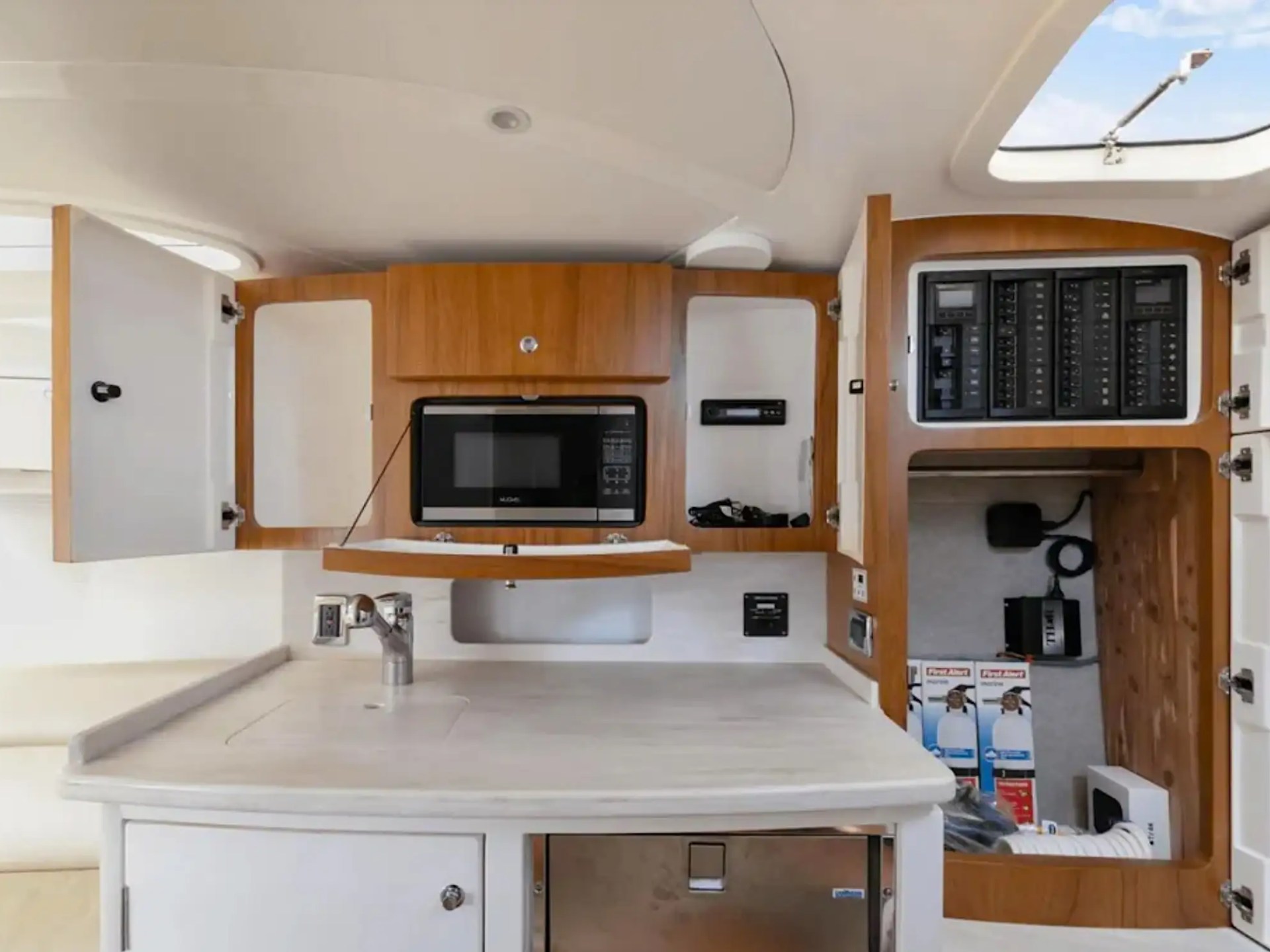 Boat kitchen with microwave, open cabinets, and electrical panels.