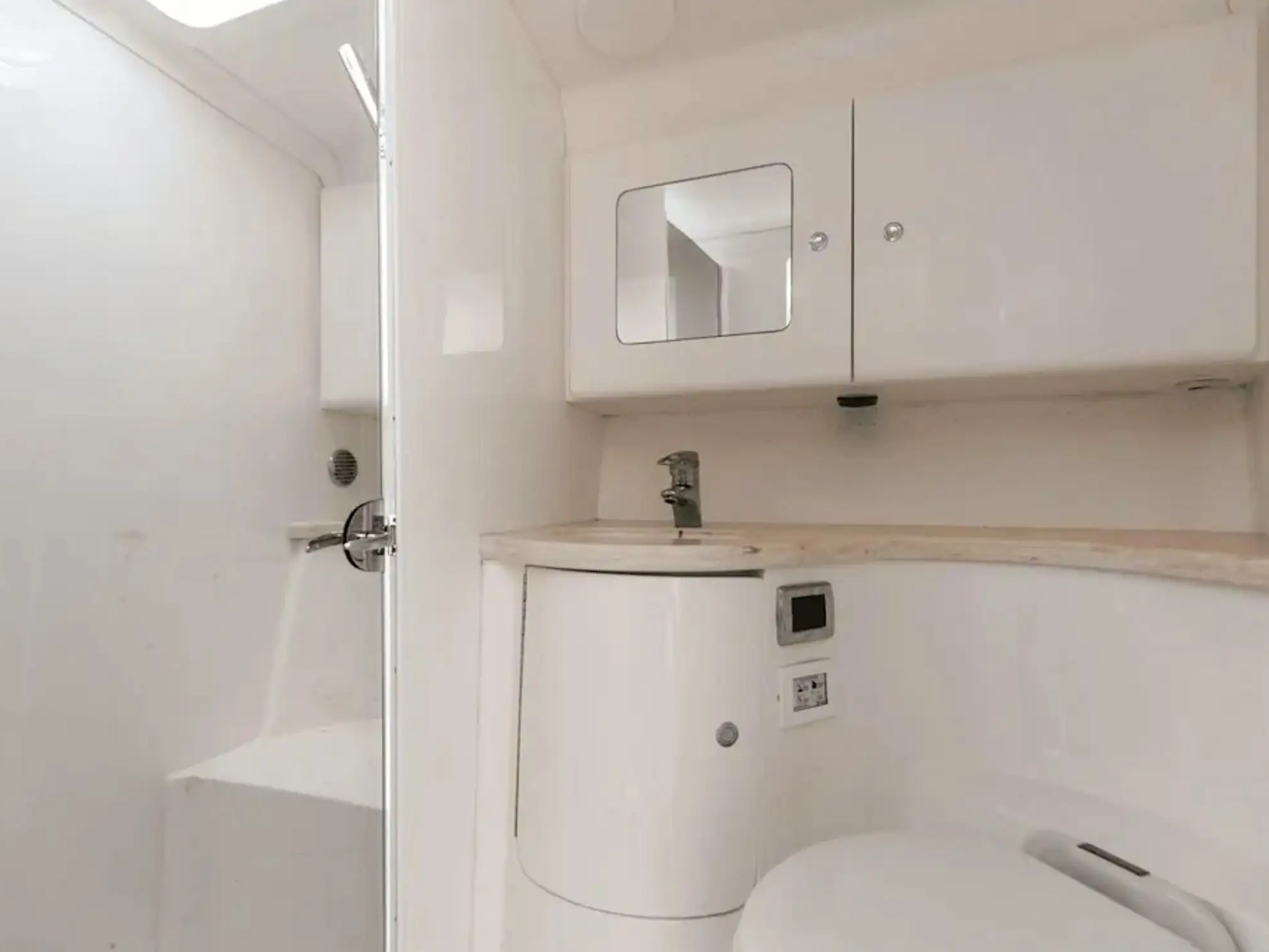 Compact white bathroom with shower, sink, mirror cabinet, and toilet.