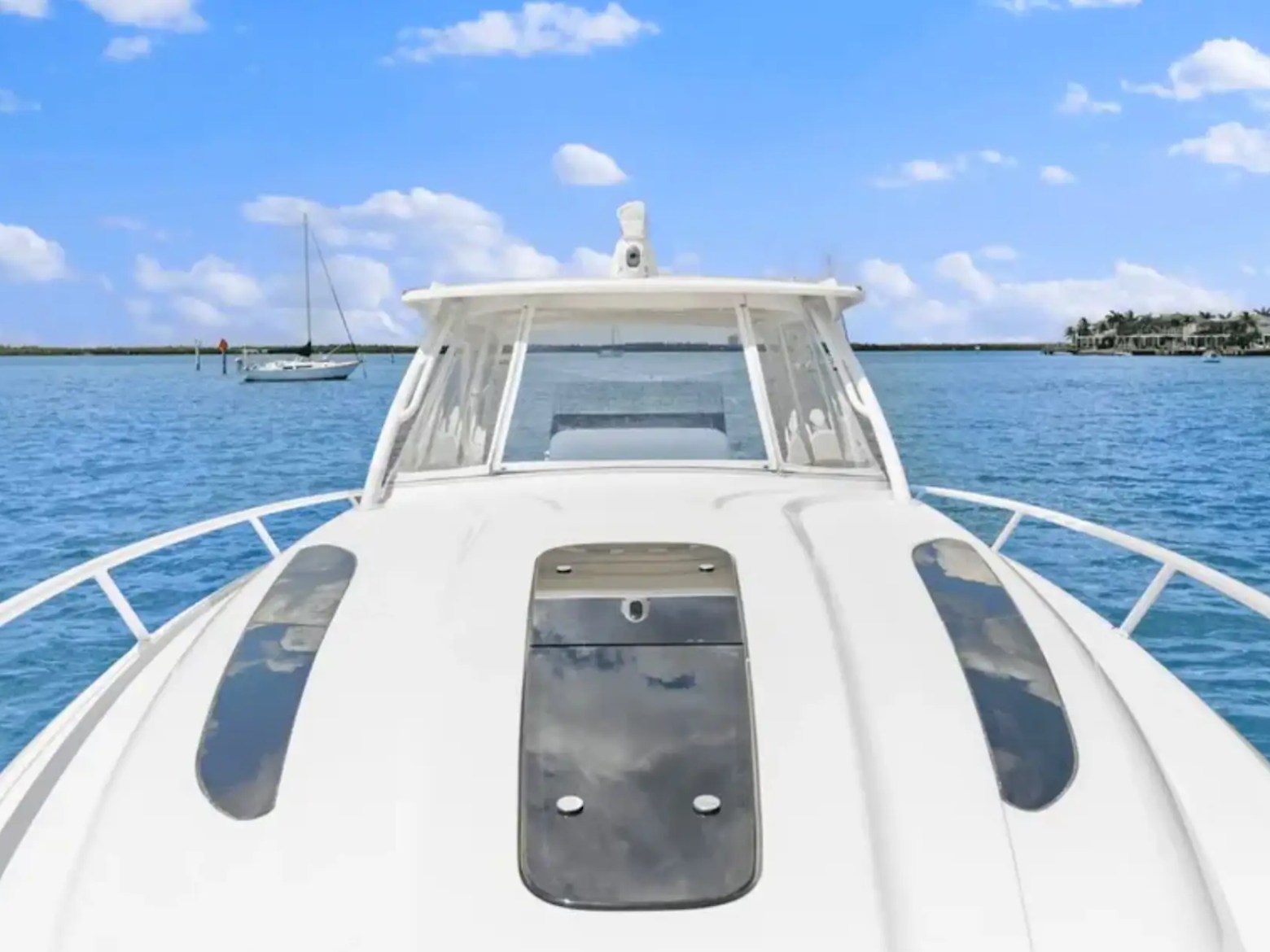 Front view of a yacht on calm blue water with a clear sky and distant boats.