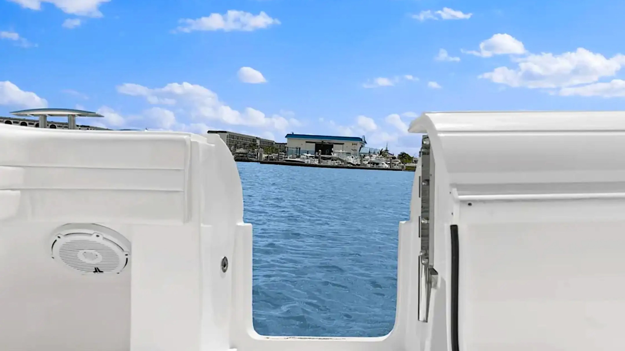 View of harbor and boats from a white boat's cockpit on a sunny day.