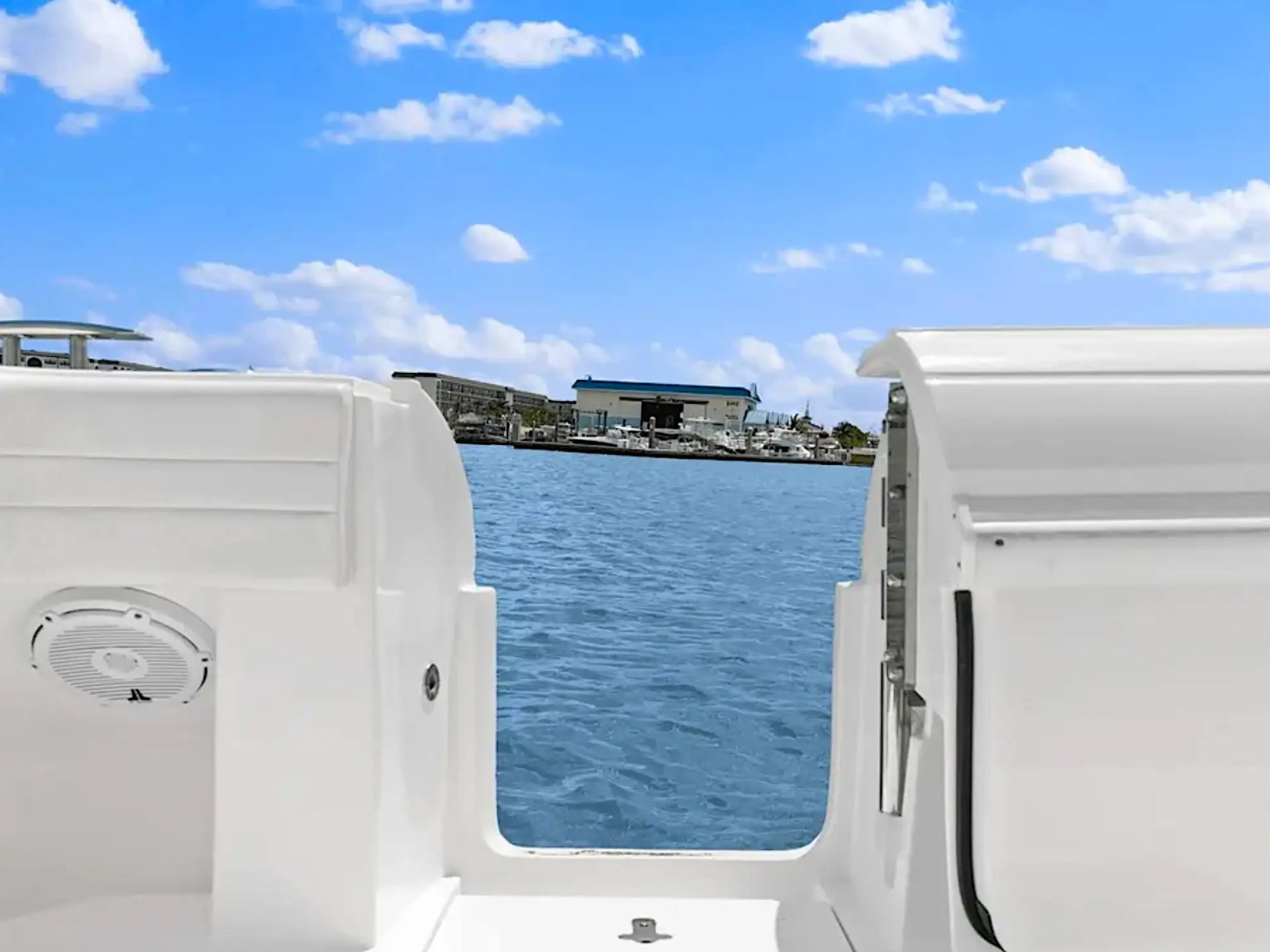 View of harbor and boats from a white boat's cockpit on a sunny day.