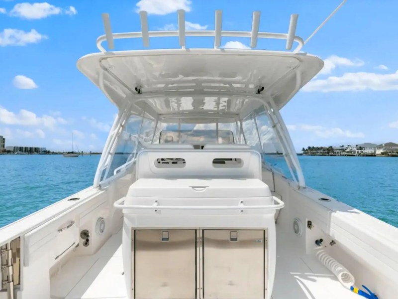 View from inside a white boat overlooking calm water and distant buildings under a clear blue sky.