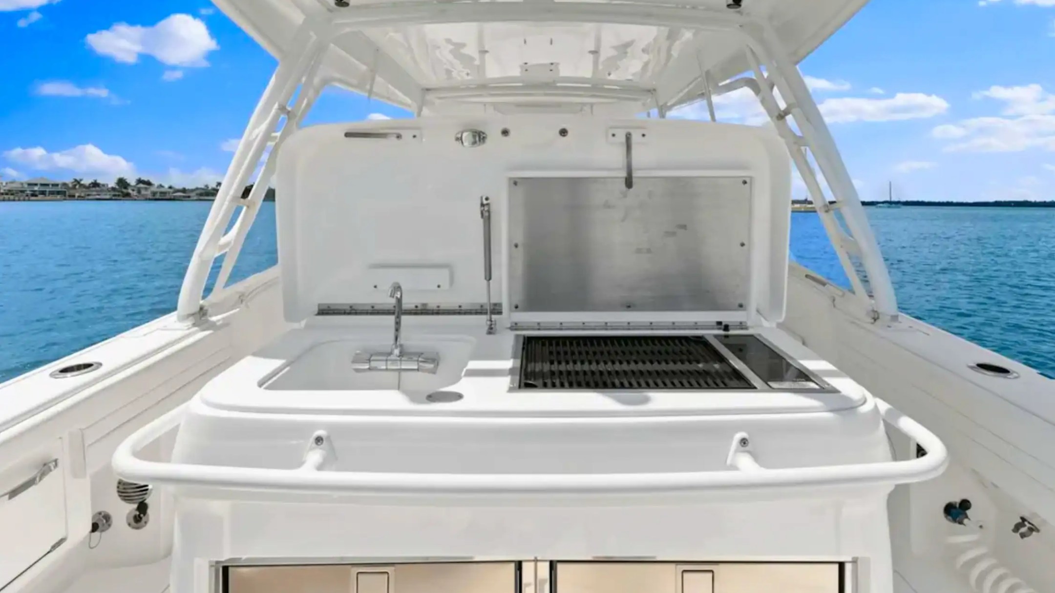 Boat deck with built-in grill and sink, ocean view in the background.