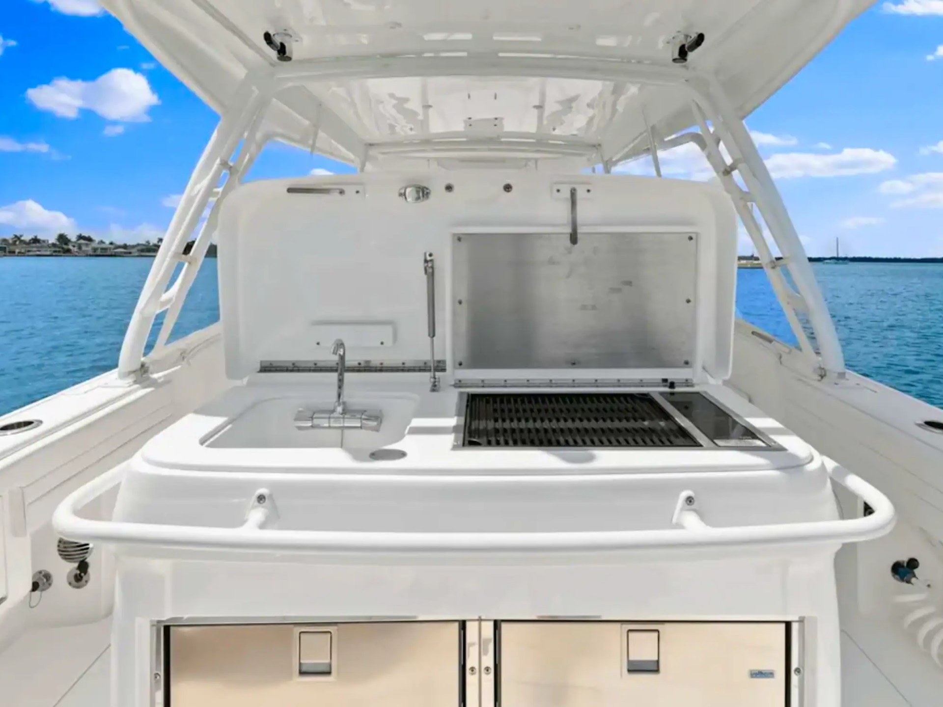 Boat deck with built-in grill and sink, ocean view in the background.