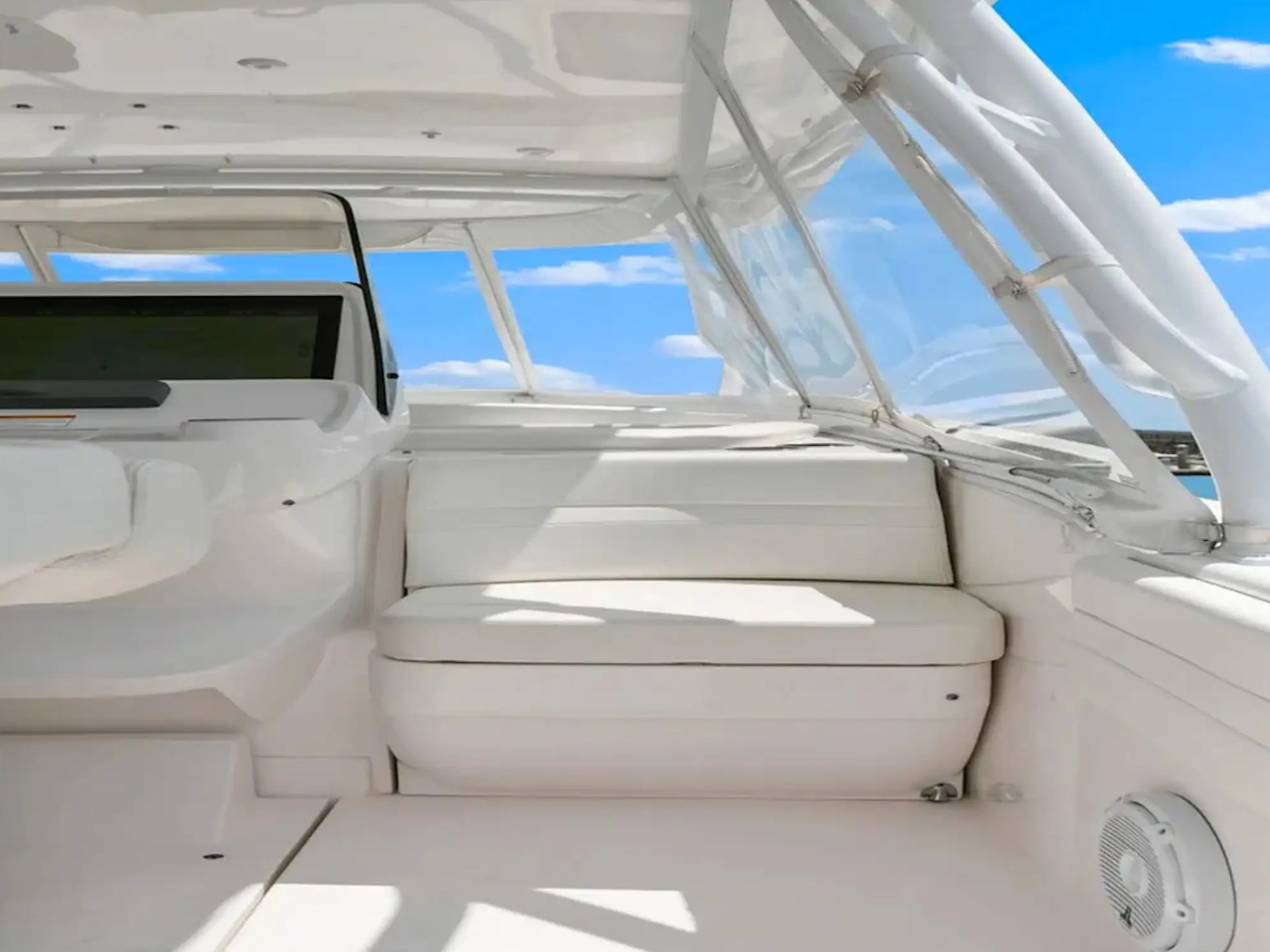 Interior of a white boat with seating and a clear blue sky outside.