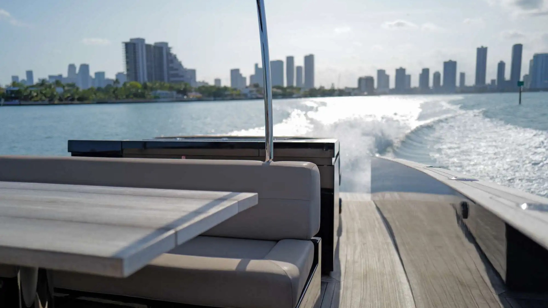 View from a boat's rear with a city skyline across the water in the background.