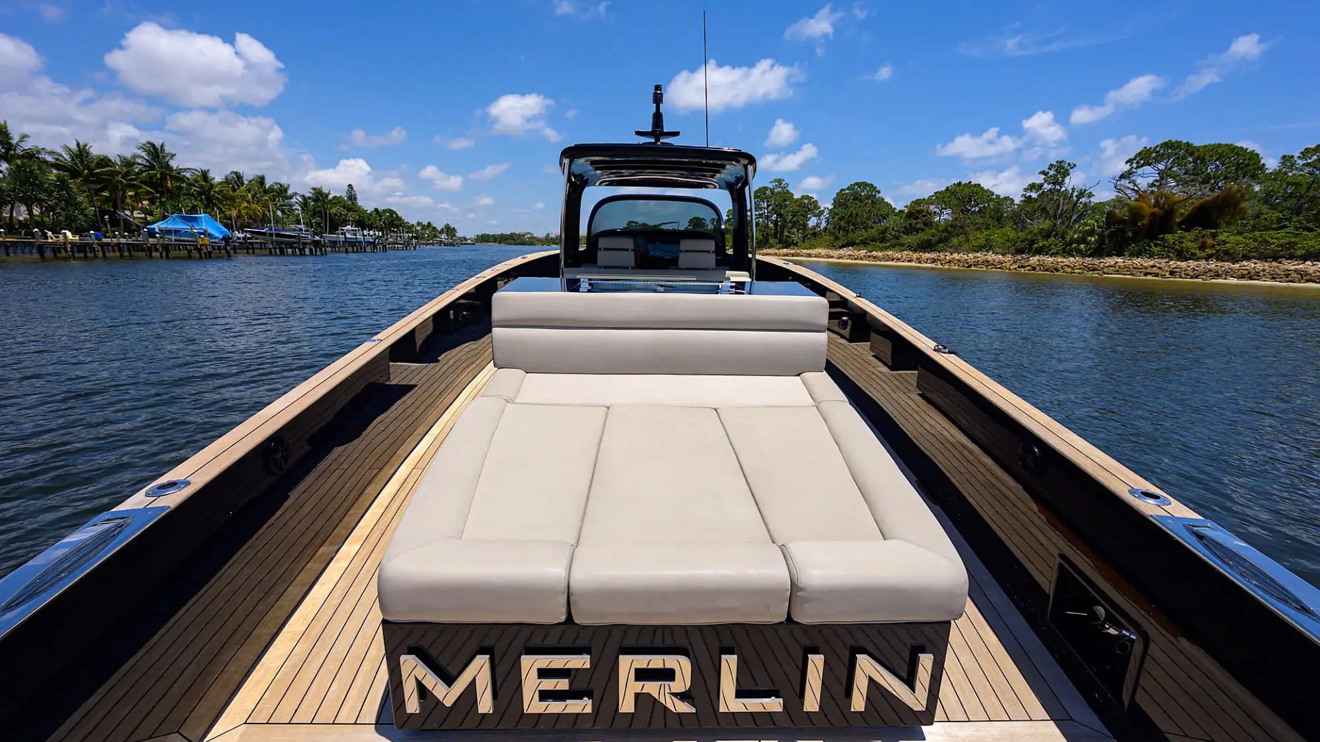 Luxury boat with beige seating on a river, palm trees in the background.