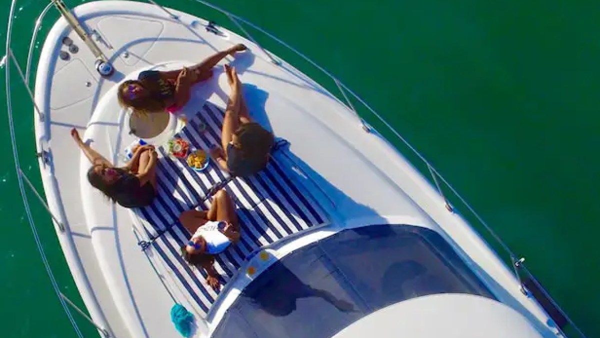 45 Meridian Boat Rental aerial view featuring guests relaxing on the bow sunpad while anchored on emerald waters near Monument Island, showcasing a luxury Miami boating experience.