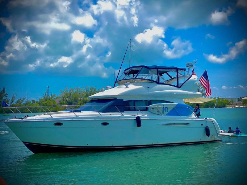 45 Meridian Boat Rental anchored near Nixon Sandbar with paddleboarders beside the yacht, featuring a spacious flybridge, American flags, and crystal-clear Miami waters.