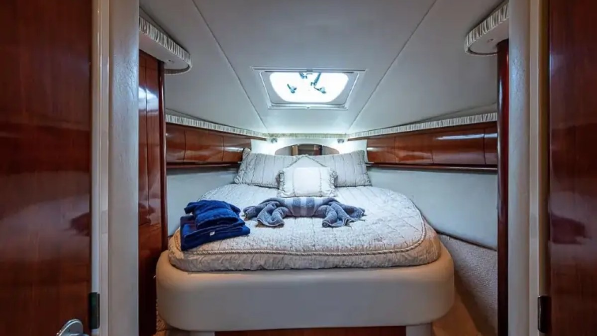 Cozy yacht bedroom with double bed, skylight, and folded towels.