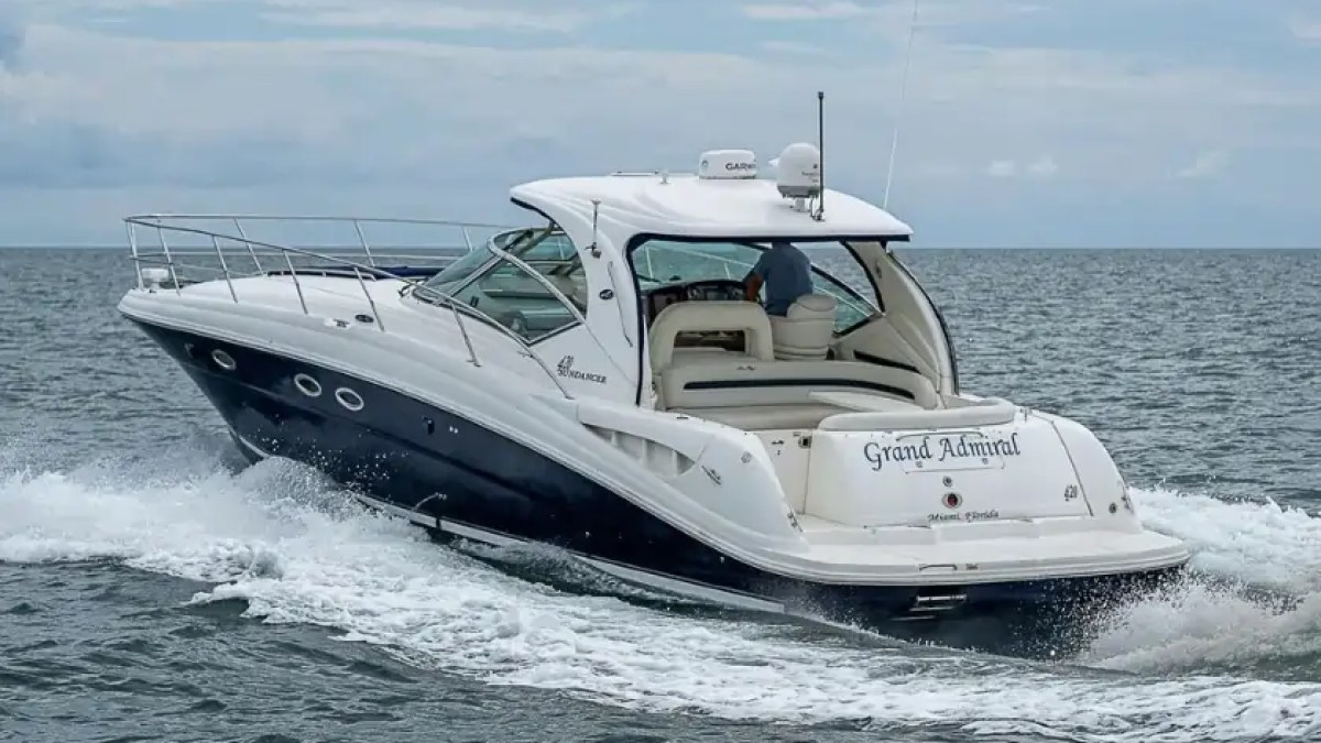 A white motor yacht cruising on the ocean under a cloudy sky.