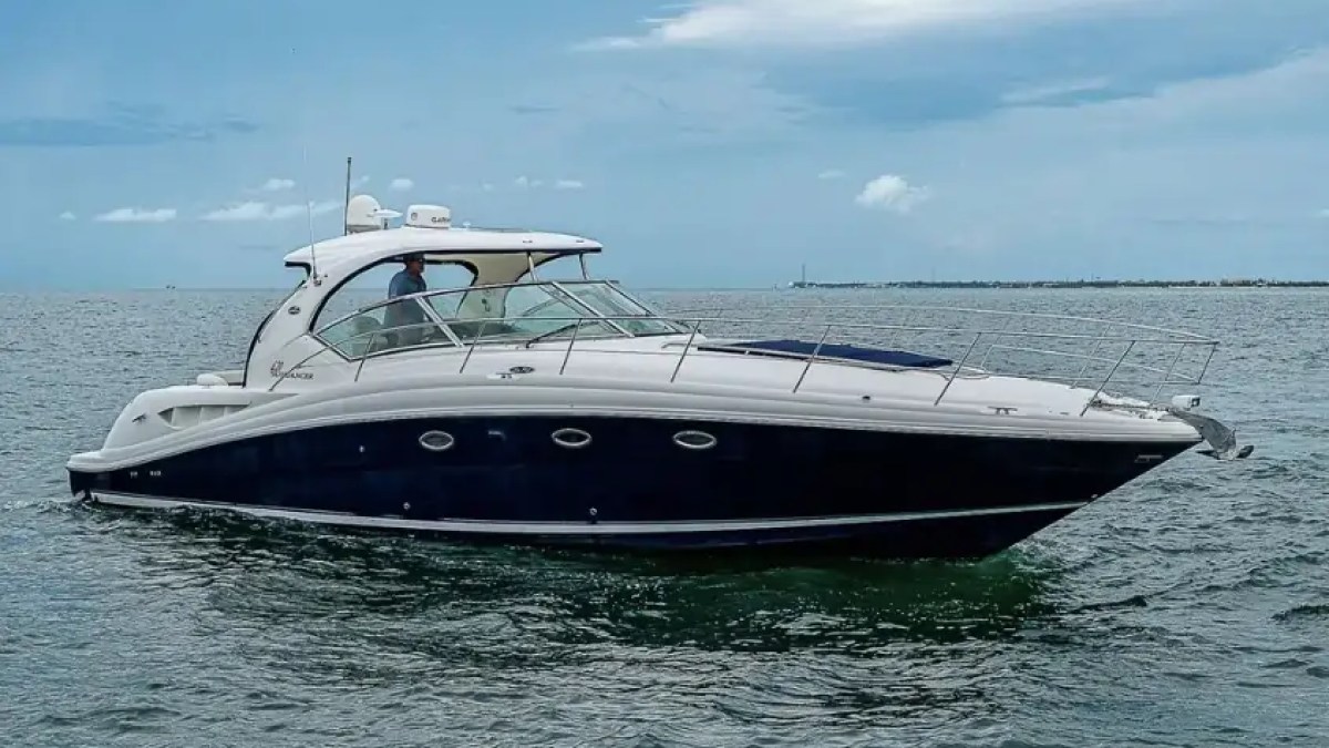 A motor yacht cruising on calm sea under a partly cloudy sky.