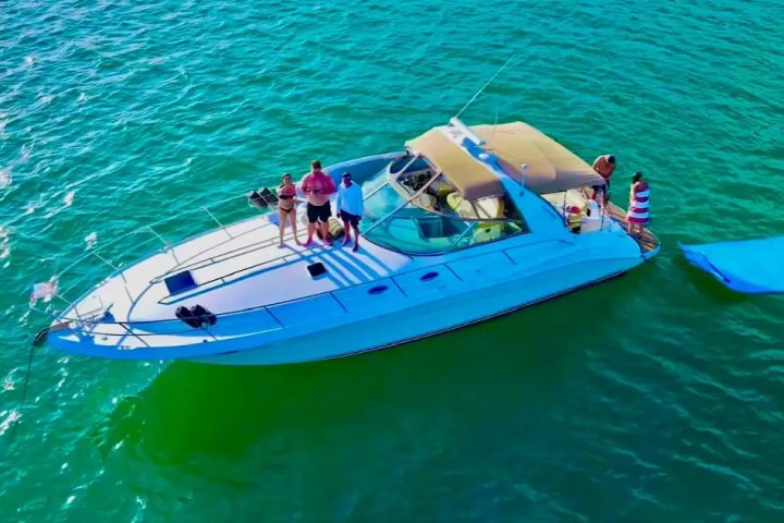 People on a yacht in clear green water, with a blue float in the water.