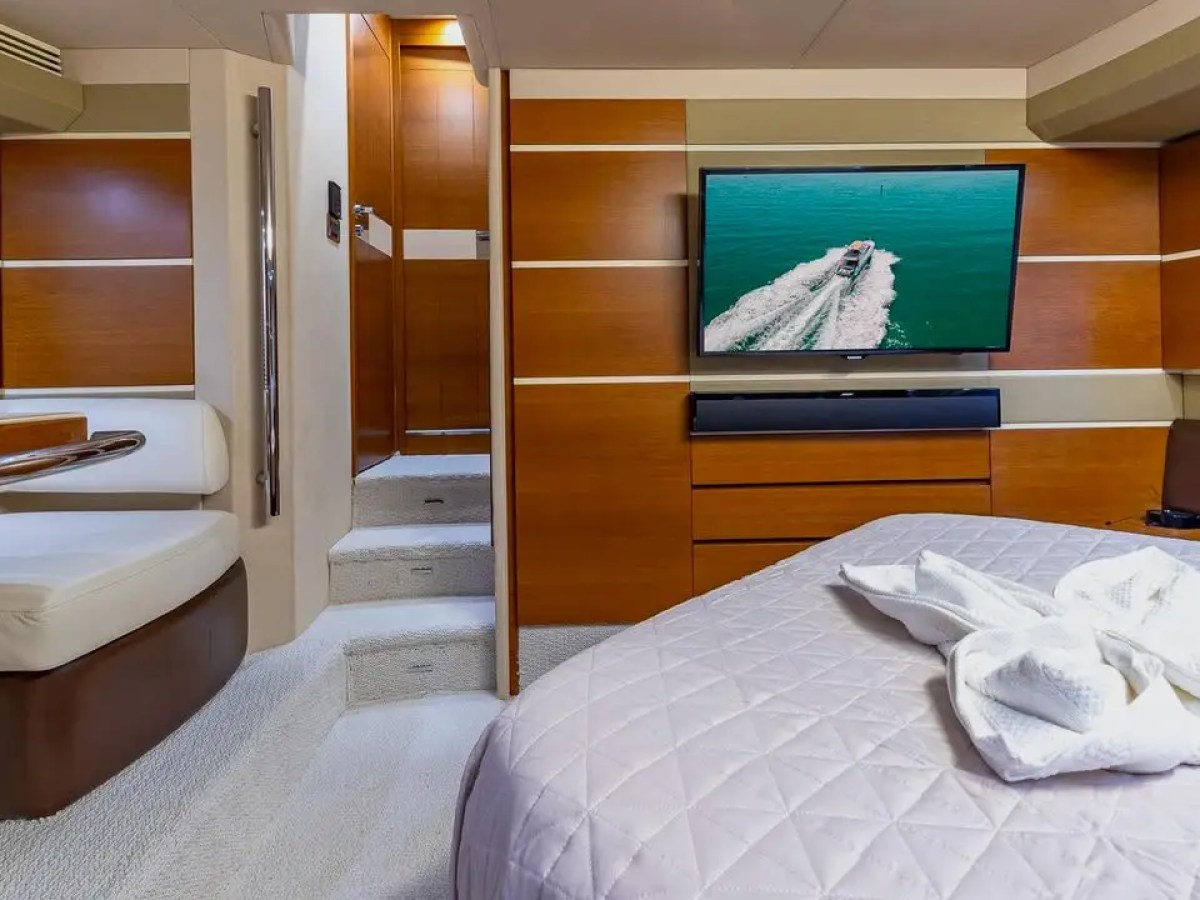 50 Azimut Yacht Charter master stateroom featuring premium bedding, integrated entertainment system, modern wood finishes, and luxury accommodations in Downtown Miami waters