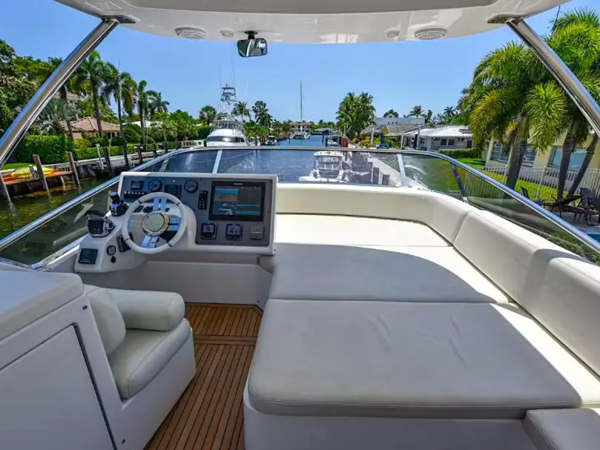 50 Azimut Yacht Charter flybridge helm featuring lounge sun pad seating, navigation controls, and scenic canal views near Coconut Grove, Coral Gables, and Biscayne Bay waterways